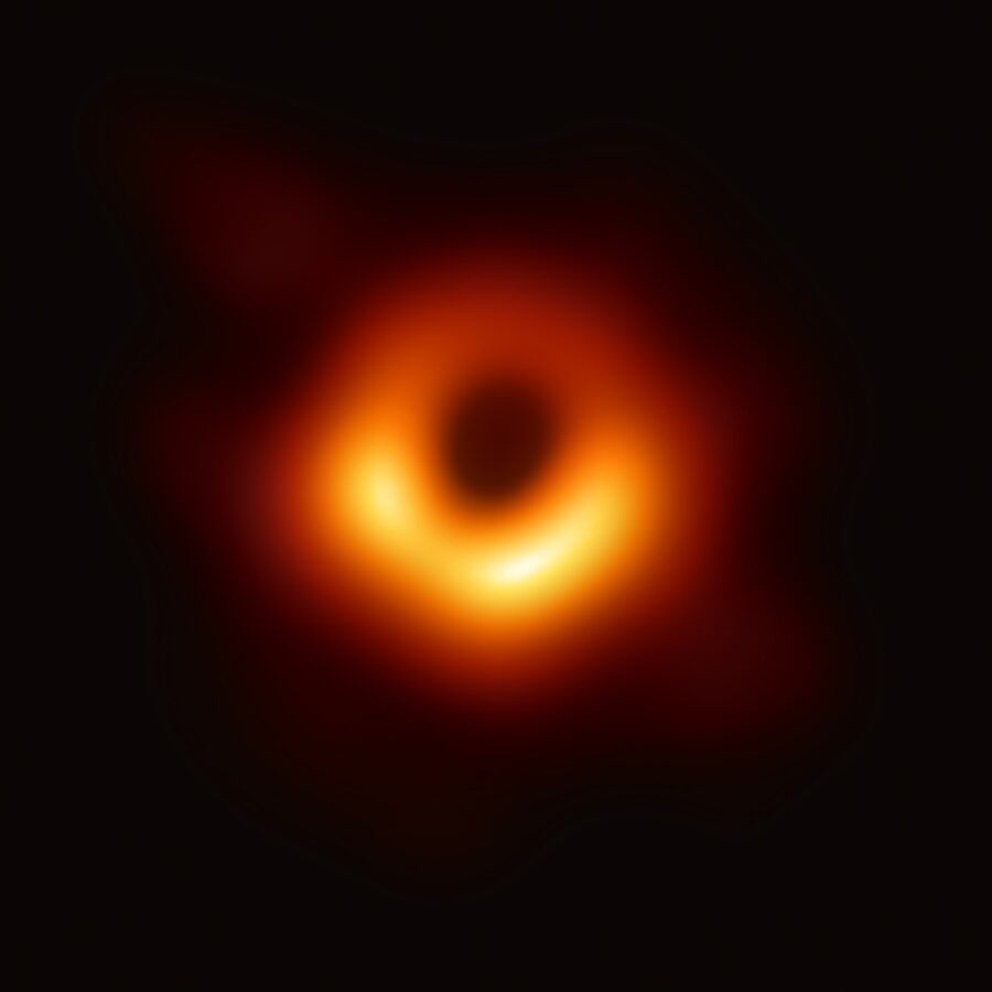 The real 2019 Event Horizon Telescope image of the M87 black hole, showing a glowing orange ring around a dark shadow